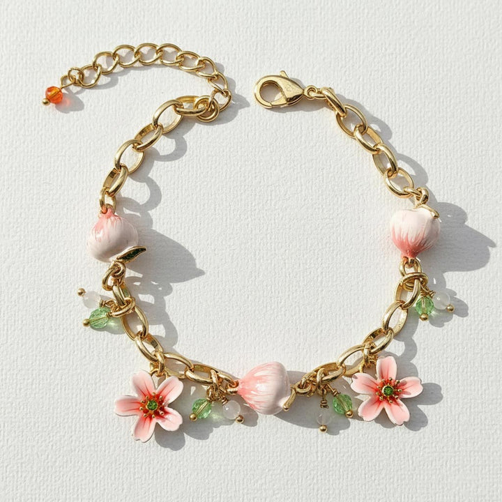 Gold bracelet with floral charms on a light background