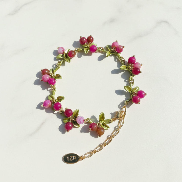 Bracelet with pink beads and gold chain on a white background