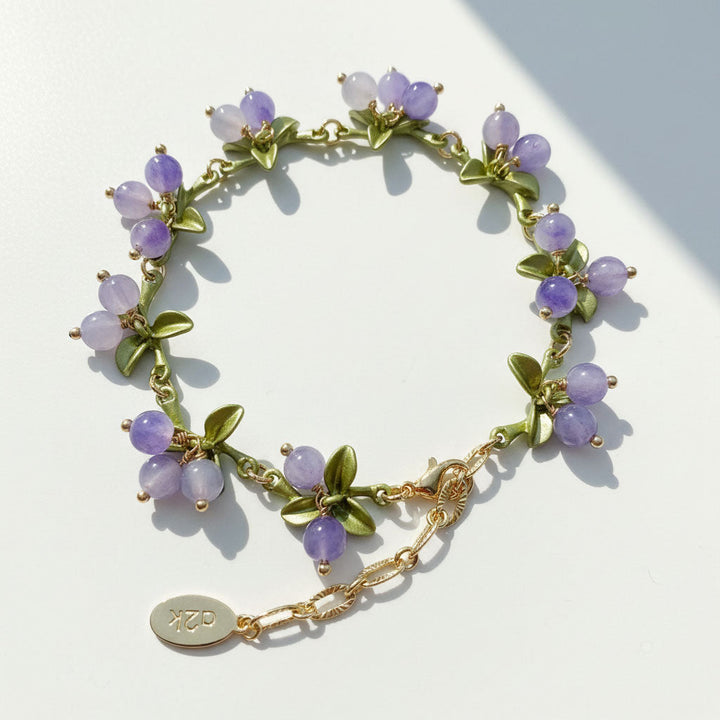 Bracelet with purple beads and gold chain on a light background