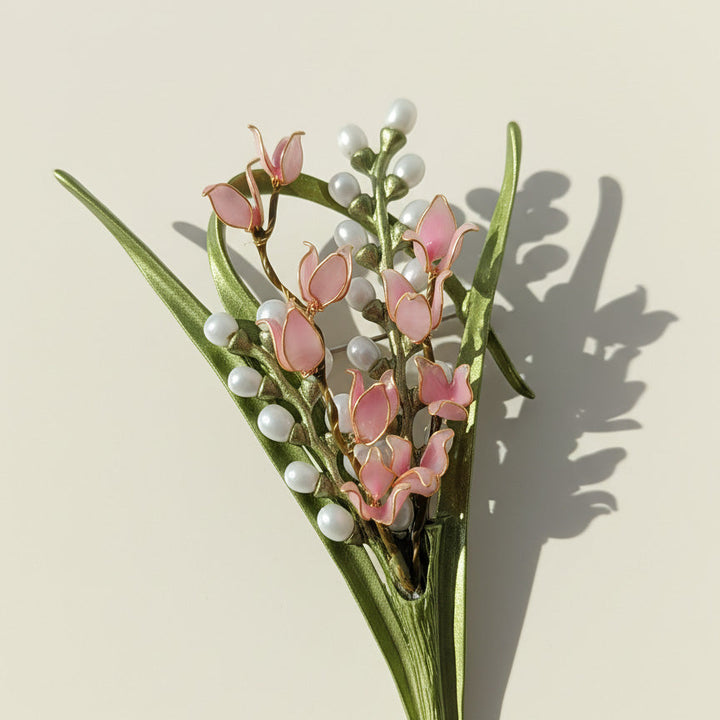 Close-up of lily of the valley brooch showing resin petals and enamel leaves