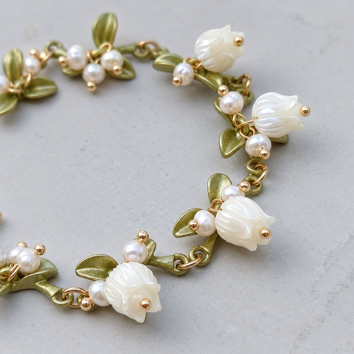 Close-up of a Lily of the Valley bracelet with hand-carved mother-of-pearl flowers and freshwater pearls.