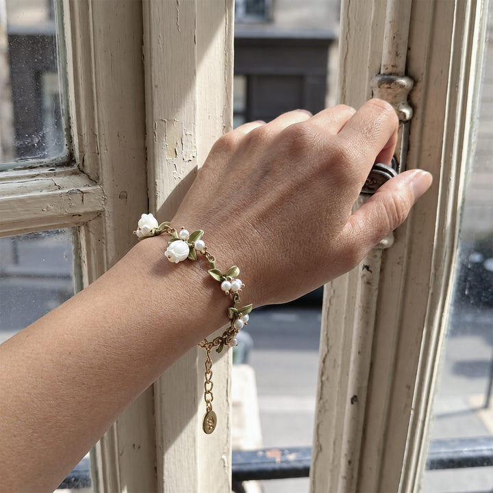 Model wearing a Lily of the Valley pearl bracelet while reaching toward a vintage window handle.