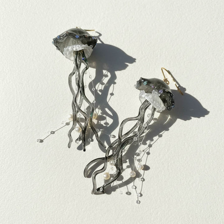Jellyfish-shaped earrings with crystal-like bodies on a white background