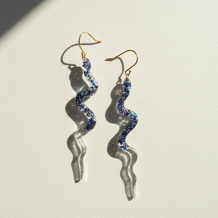 Spiral-shaped earrings with blue gemstones on a light background