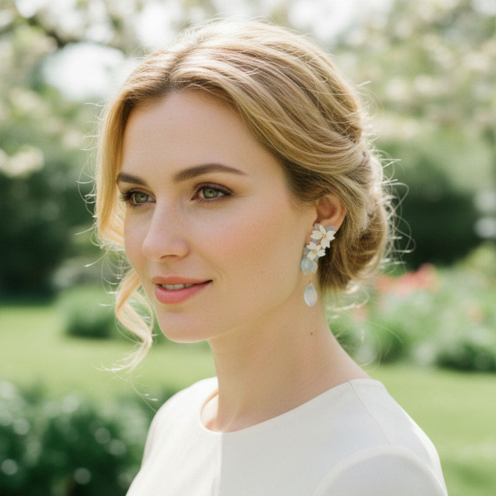 Woman with styled hair and earrings in a garden setting