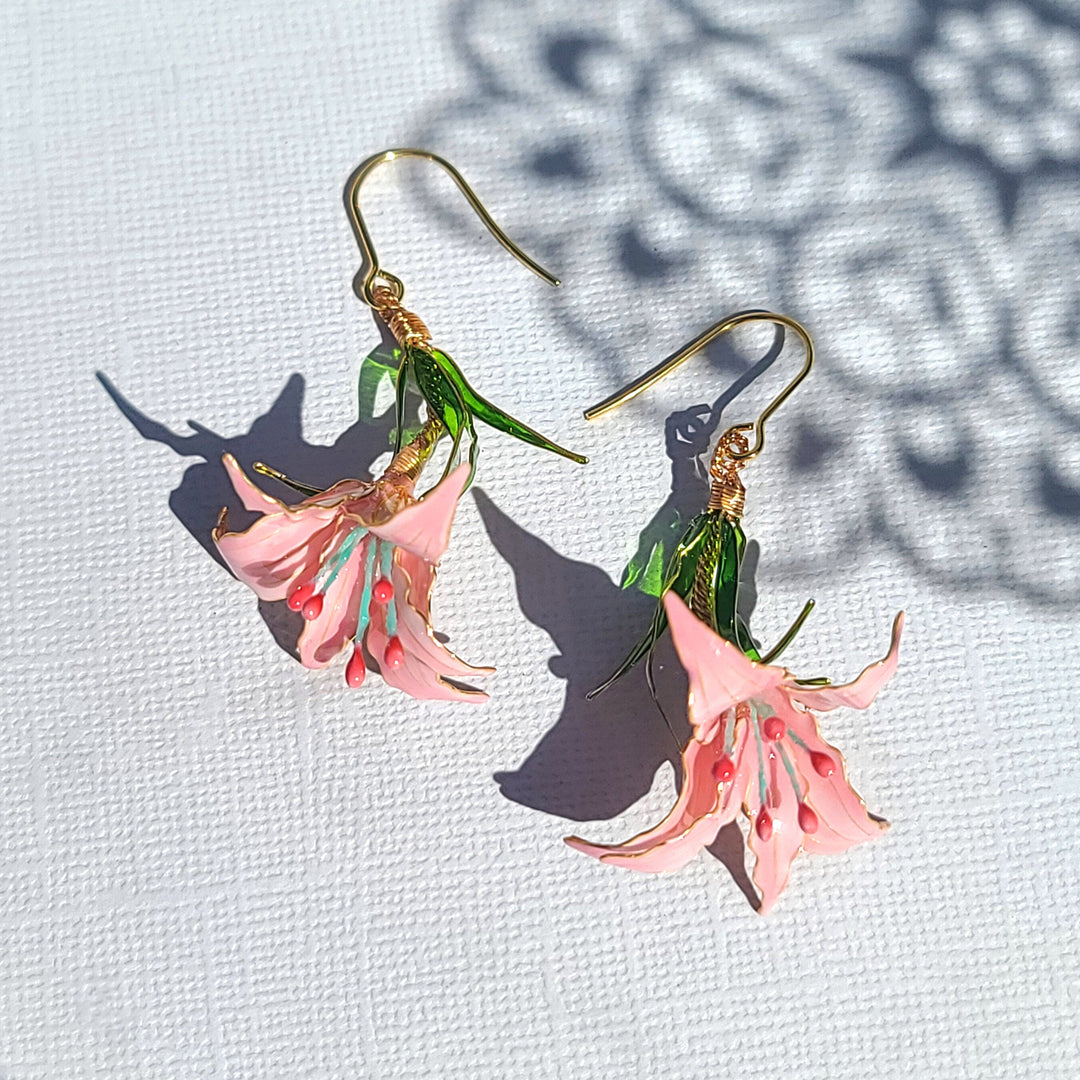 Hand-painted pink floral drop earrings with green leaves and gold hooks, inspired by blooming fuchsia flowers.