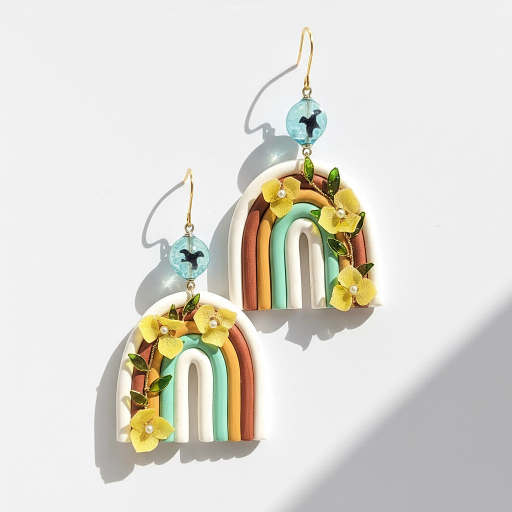 Colorful rainbow arch earrings with hydrangea flowers and resin details photographed in sunlight.