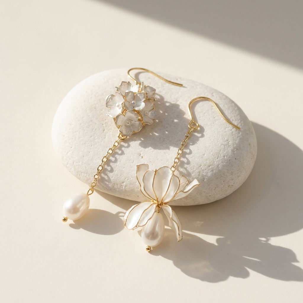 Delicate gold and pearl earrings on a white stone with soft shadows