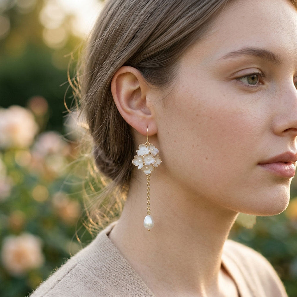 Close-up of a woman wearing pearl earrings with a blurred natural background