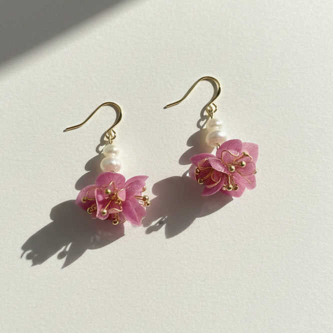 Pair of pink floral earrings with gold accents on a light background