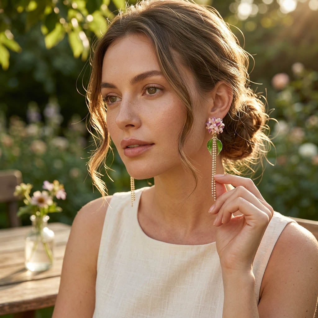 Woman wearing long Hydrangea earrings outdoors with greenery in the background