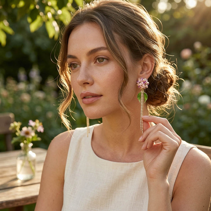 Woman wearing long Hydrangea earrings outdoors with greenery in the background