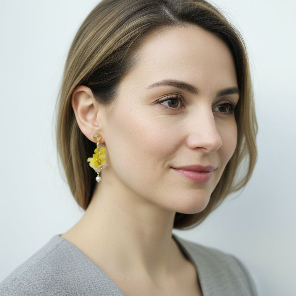 Woman wearing yellow floral earrings against a plain background