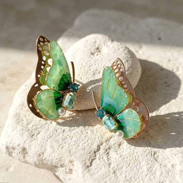 December birthstone butterfly earrings with gold accents on a textured stone surface