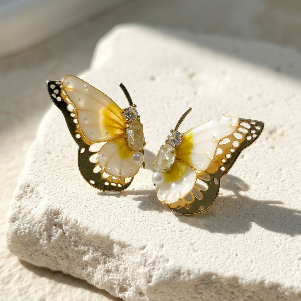April birthstone butterfly-shaped earrings with yellow and white details on a textured surface