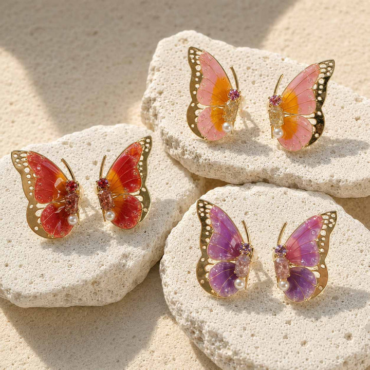Butterfly-shaped birthstone earrings on stones with a natural background
