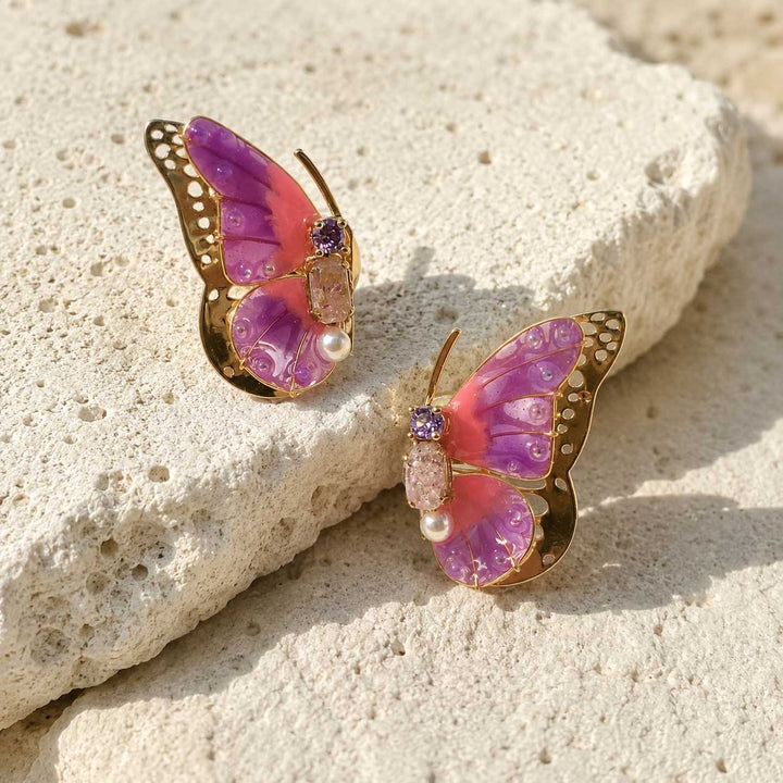 June birthstone Butterfly-shaped earrings with purple and pink colors on a stone surface