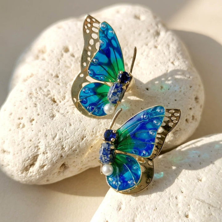 September birthstone butterfly-shaped earrings on a white stone surface