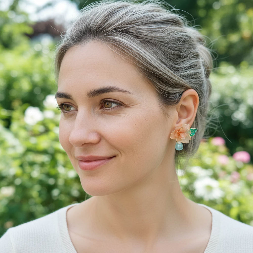 Woman wearing floral earrings with a blurred green background