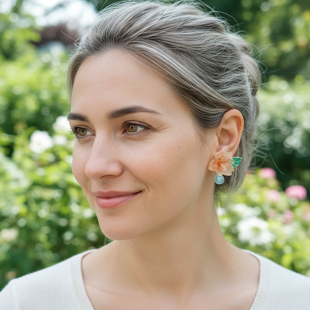 Woman wearing floral earrings with a blurred green background