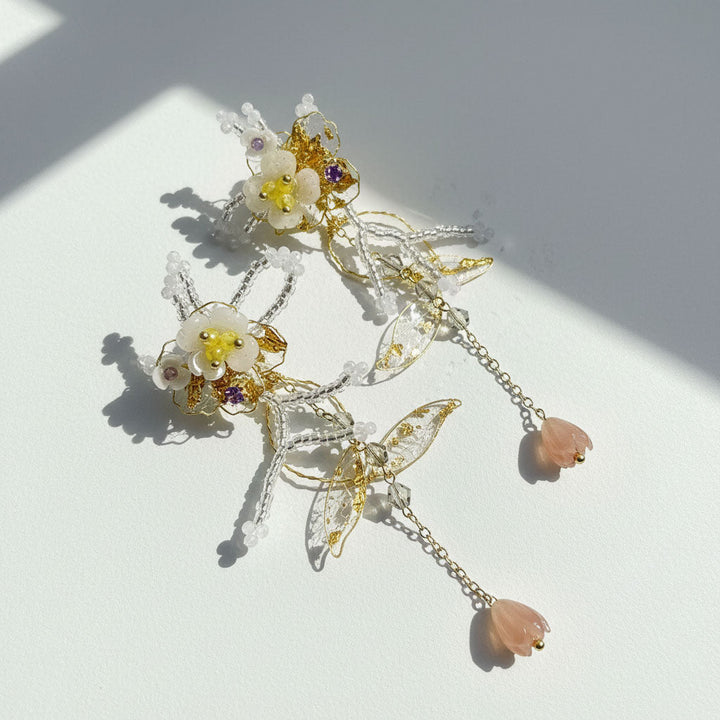 Decorative earrings with floral and butterfly designs on a light background