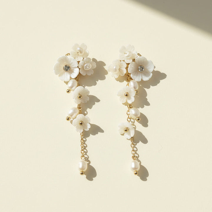 Handcrafted white floral earrings with freshwater pearls on neutral background.
