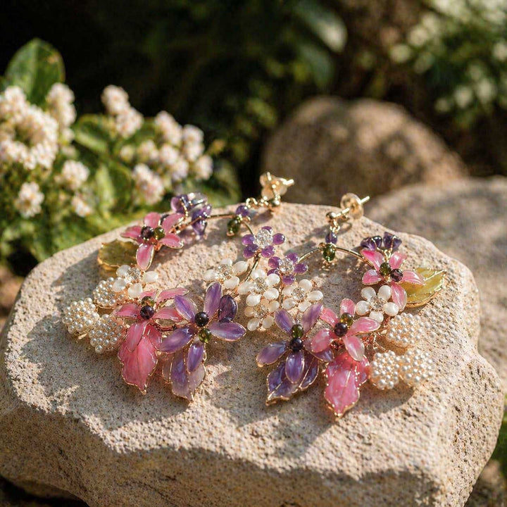 Bracelet with pink and purple floral beads on a stone surface with flowers in the background