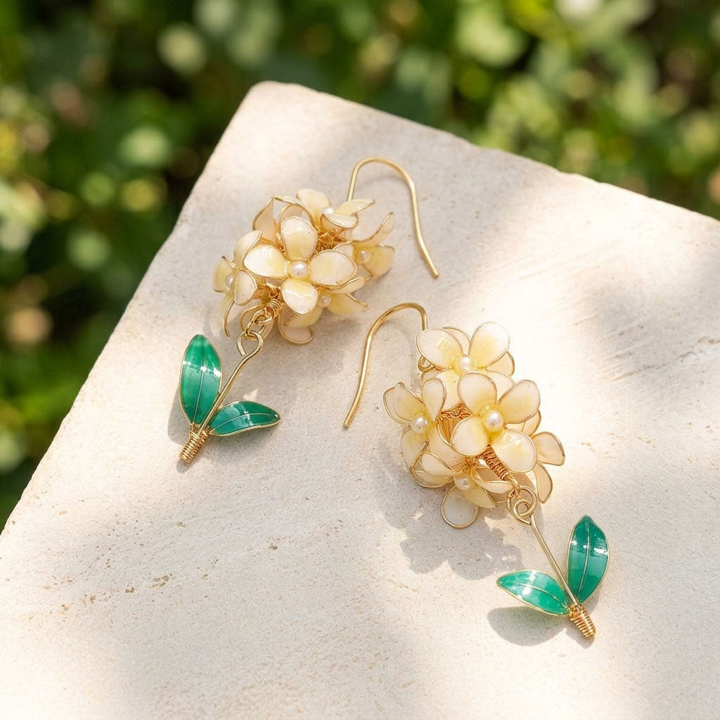 Hyacinth flower earrings with gold and green details on a stone surface with a blurred green background