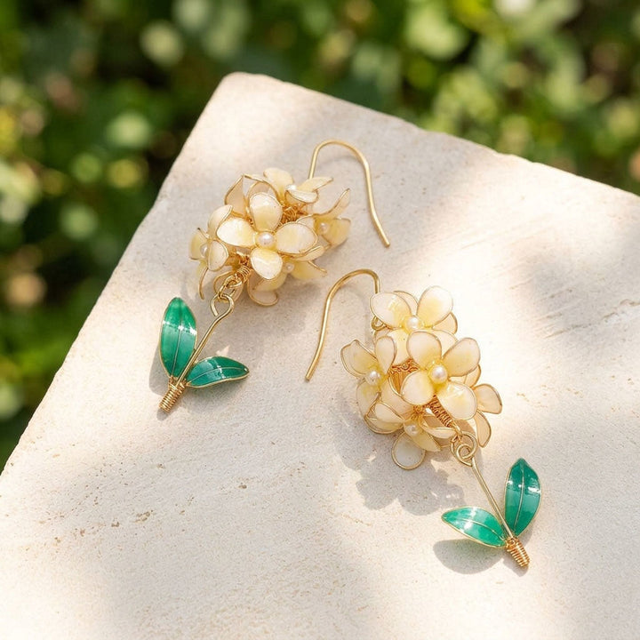 Hyacinth flower earrings with gold and green details on a stone surface with a blurred green background