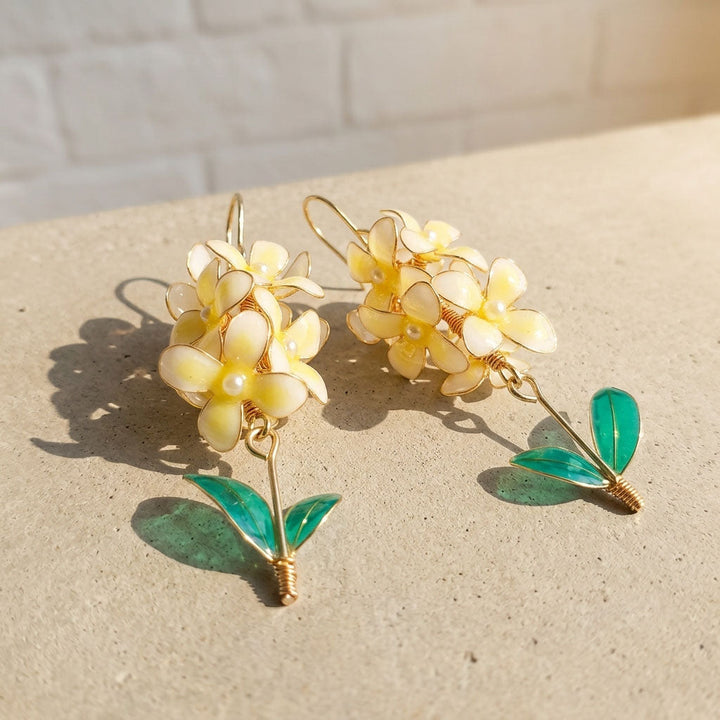 Hyacinth flower earrings with yellow flowers and green leaves on a light surface.