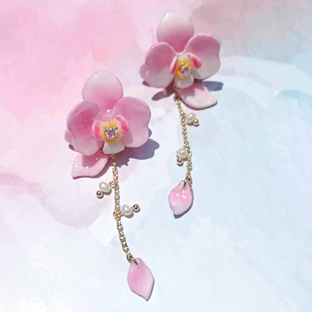 Pink floral earrings with pearl accents on a soft pink and white background