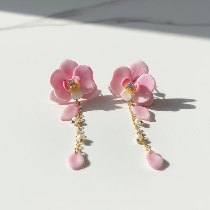 Pink floral earrings with pearl drops on a light background