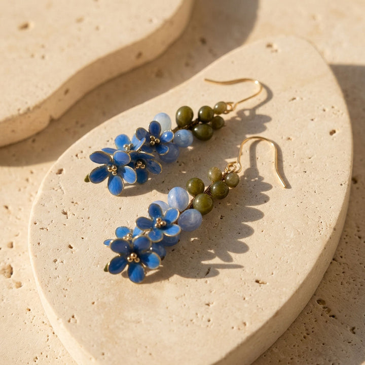 Forget-me-not floral earrings on a beige stone surface