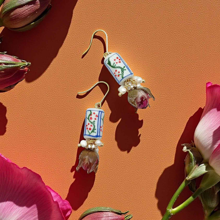 Decorative earrings with floral designs on a pink background