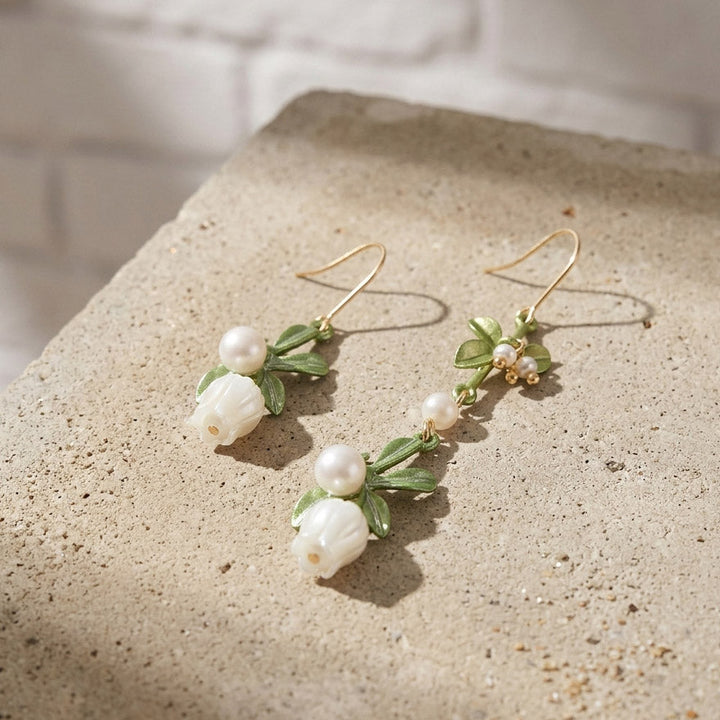 Pair of lily of the valley earrings with pearls on a textured surface