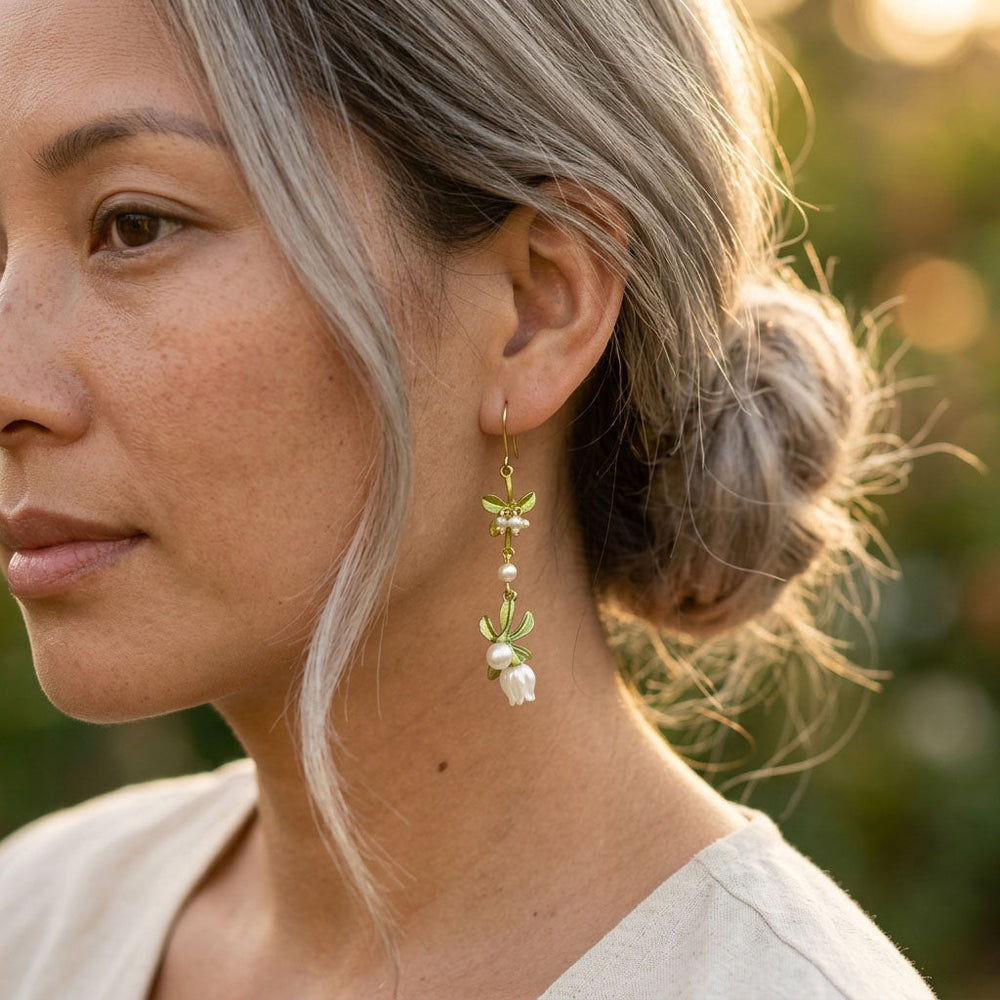 Close-up of a woman wearing floral earrings with a blurred natural background