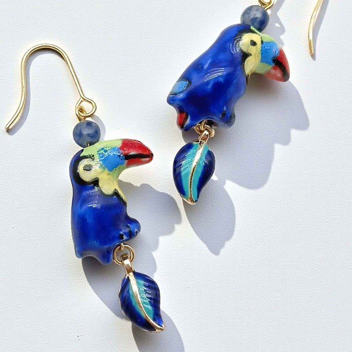 Parrot-shaped earrings with blue and gold details on a white background