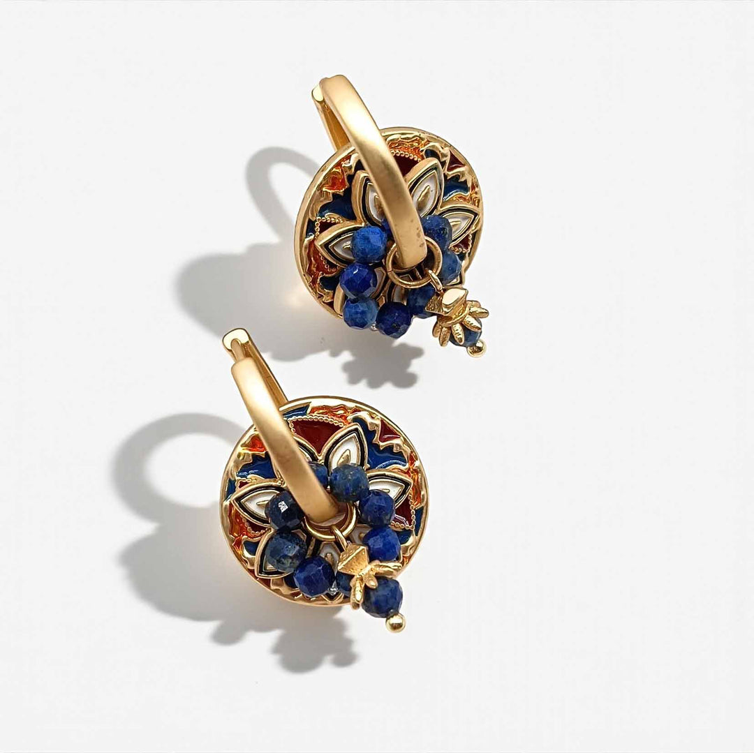 Gold earrings with blue stones on a white background