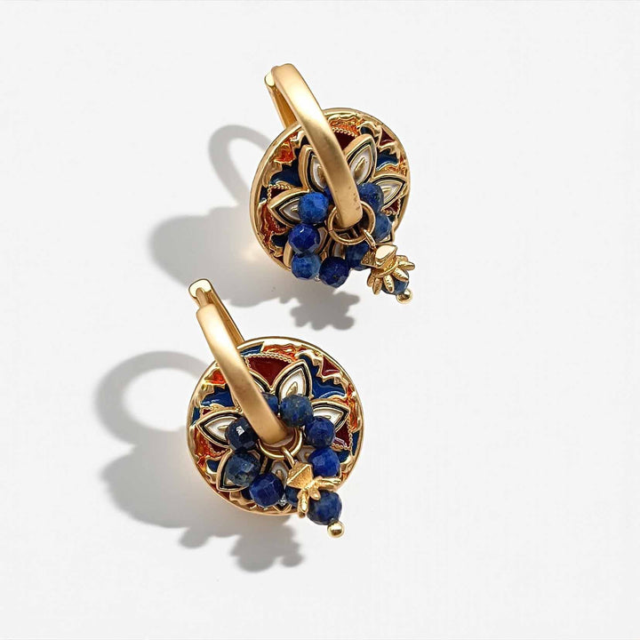 Gold earrings with blue stones on a white background