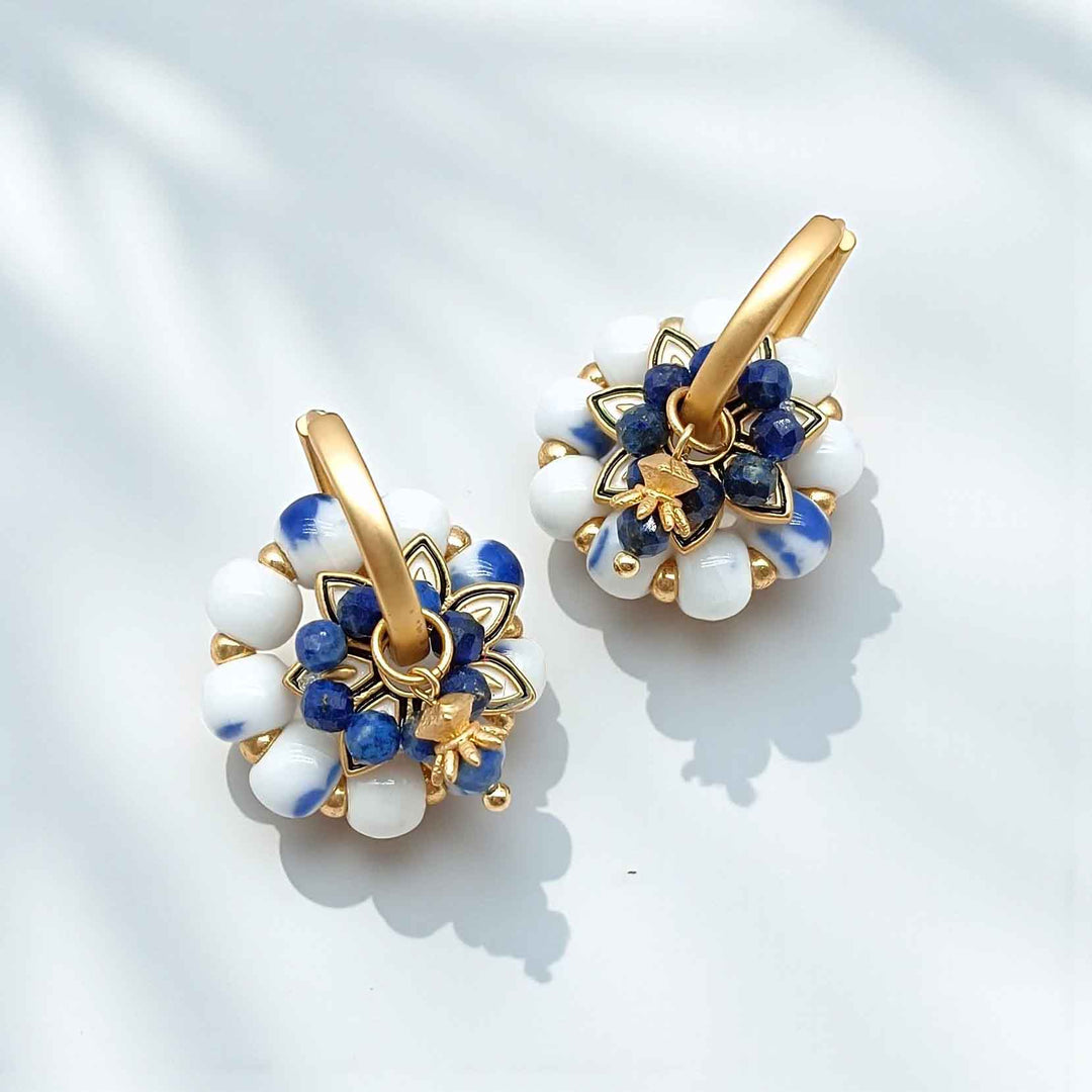 Pair of gold hoop earrings with blue and white stone accents on a light background