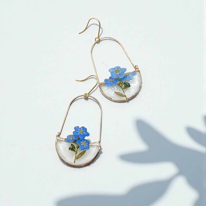 Pair of earrings with blue flowers on a light background