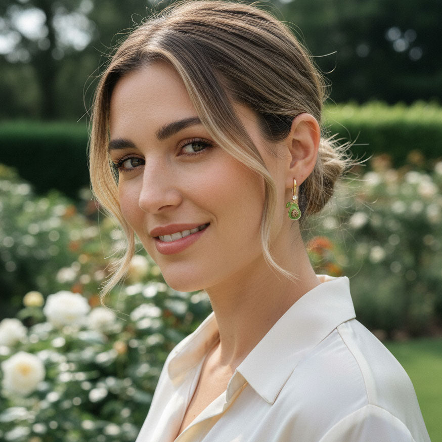 Model wearing A2K London avocado earrings outdoors, playful and elegant fruit jewelry.