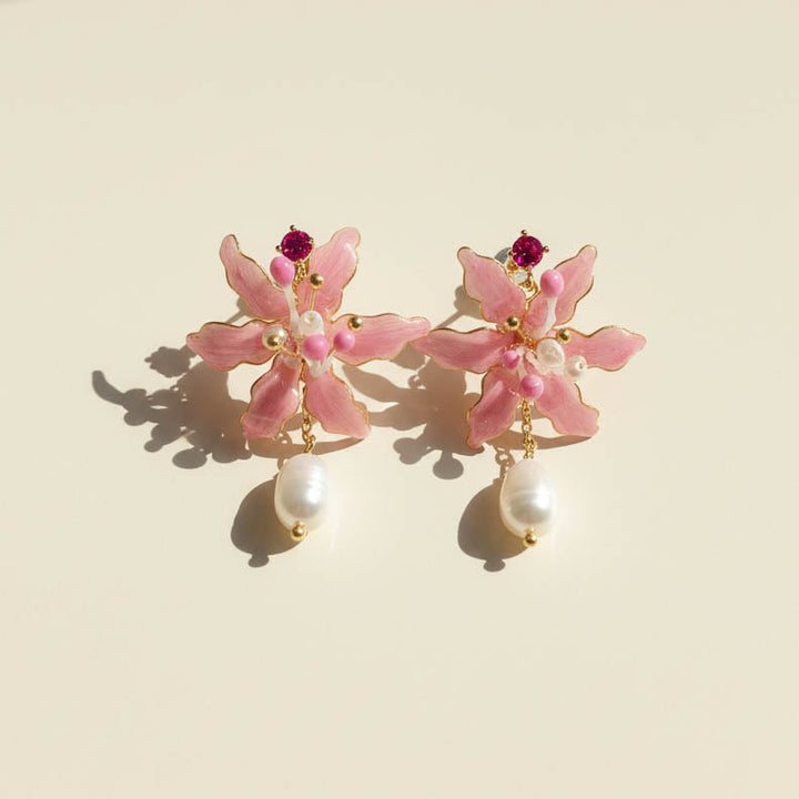 Pink spider lily flower earrings with pearl drops on a beige background