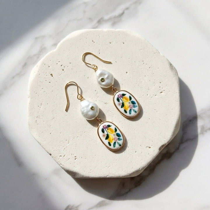 Pair of earrings with floral designs on a white stone surface
