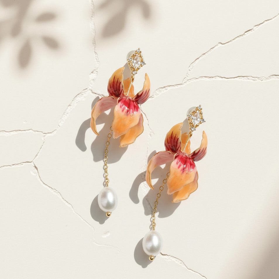 Hand-painted orchid-iris earrings with pearl drops on cracked white surface.