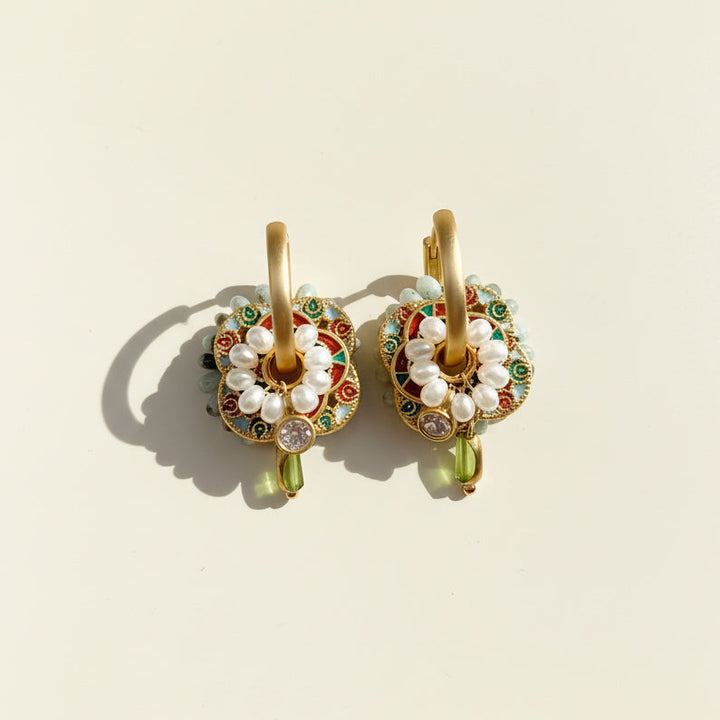 Close-up of cloisonné enamel earrings with pearl detailing in sunlight.