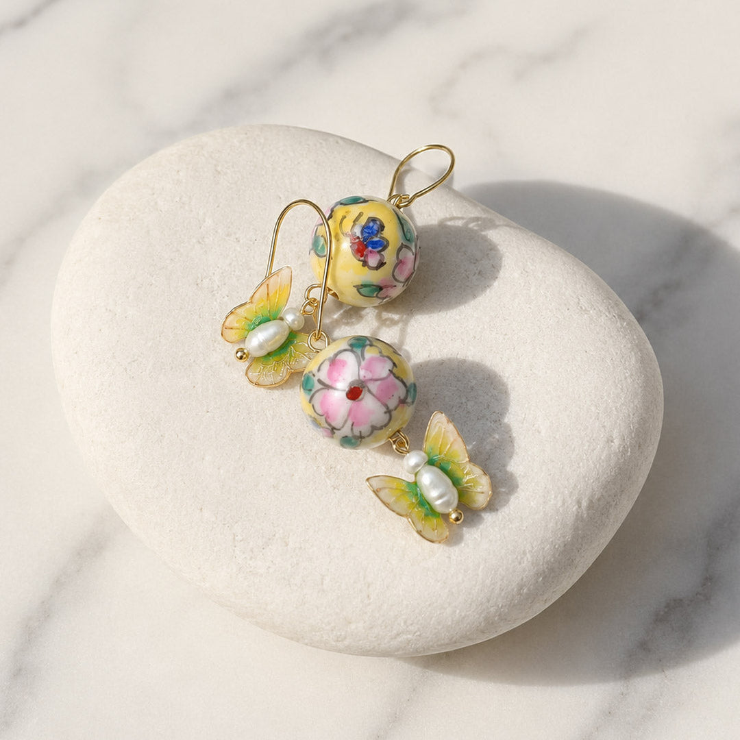 Botanical Butterfly Earrings with Freshwater Pearls and Hand-Painted Porcelain Beads on a white stone with a marble background