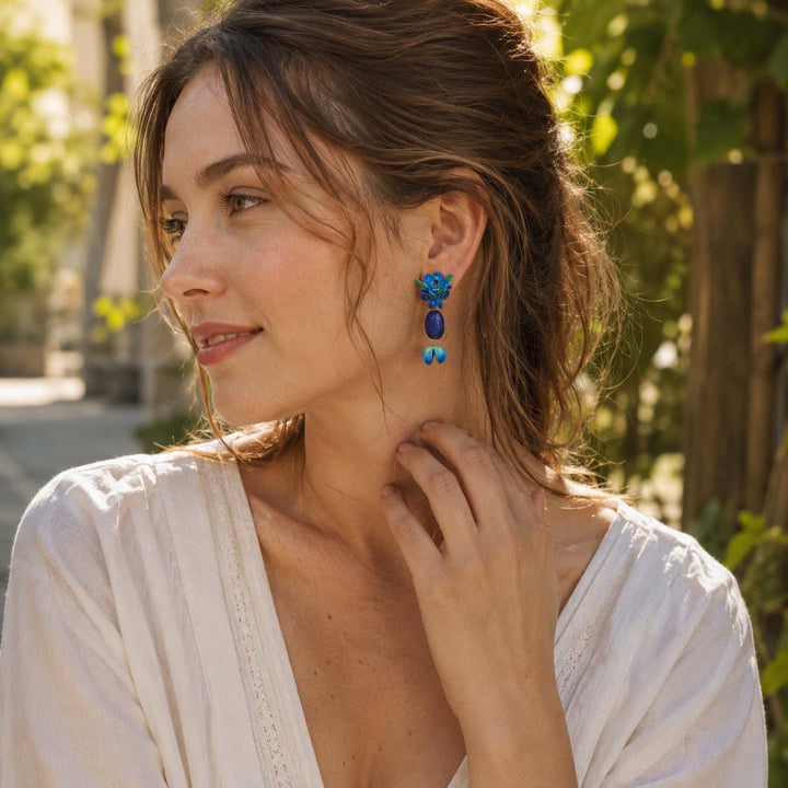 Woman wearing handcrafted blue floral lapis drop earrings in garden setting