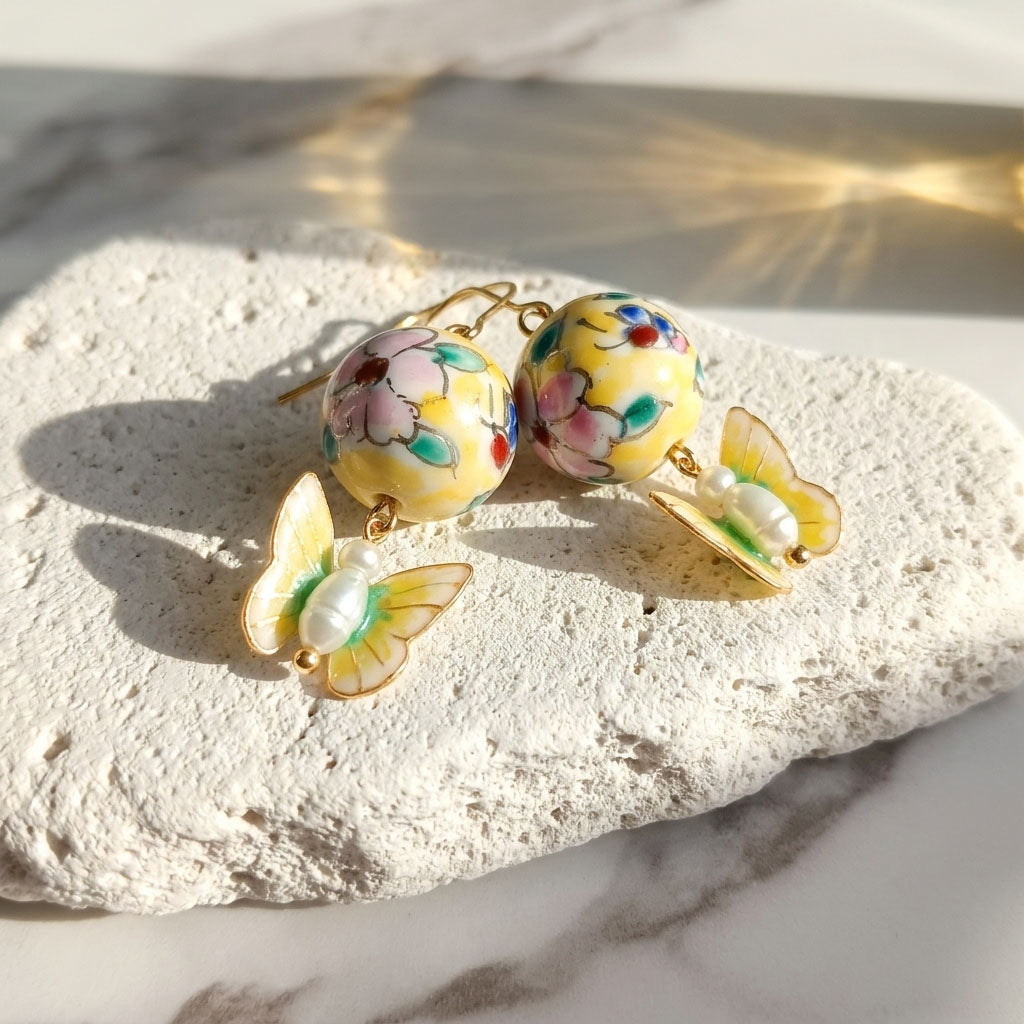 Colorful hand painted porcelain floral beads and butterfly earrings on a light stone surface