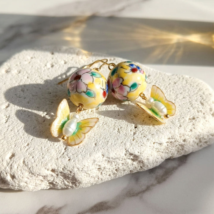 Colorful hand painted porcelain floral beads and butterfly earrings on a light stone surface